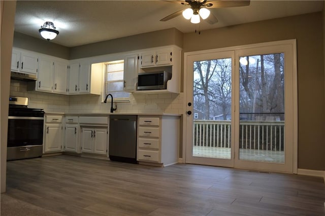 kitchen with stainless steel appliances, wood-type flooring, tasteful backsplash, and white cabinets