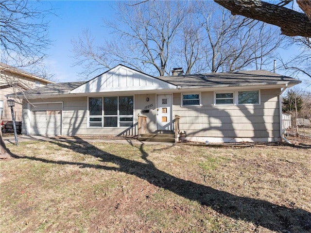 back of property featuring a garage and a yard