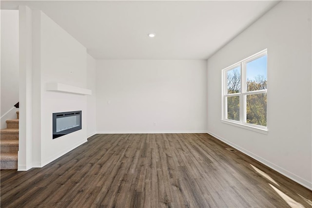 unfurnished living room featuring heating unit and dark hardwood / wood-style floors