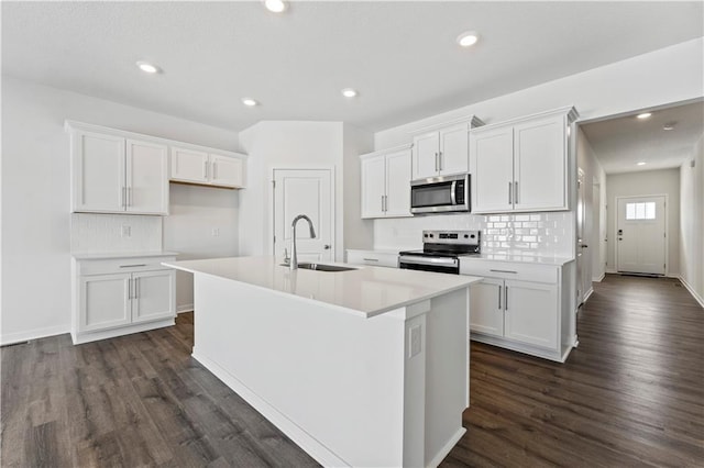 kitchen with sink, white cabinetry, appliances with stainless steel finishes, dark hardwood / wood-style floors, and a kitchen island with sink