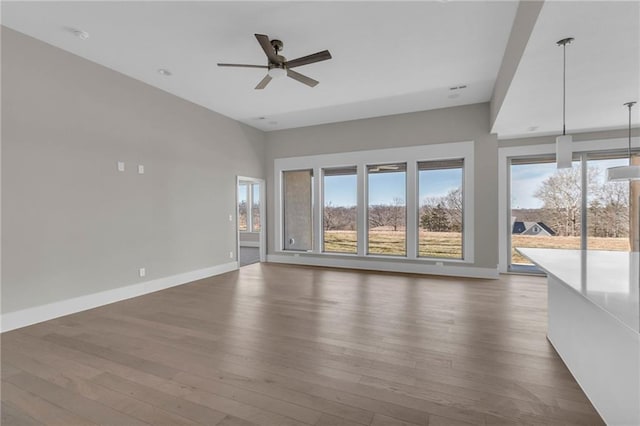 unfurnished living room featuring dark wood finished floors, baseboards, and ceiling fan