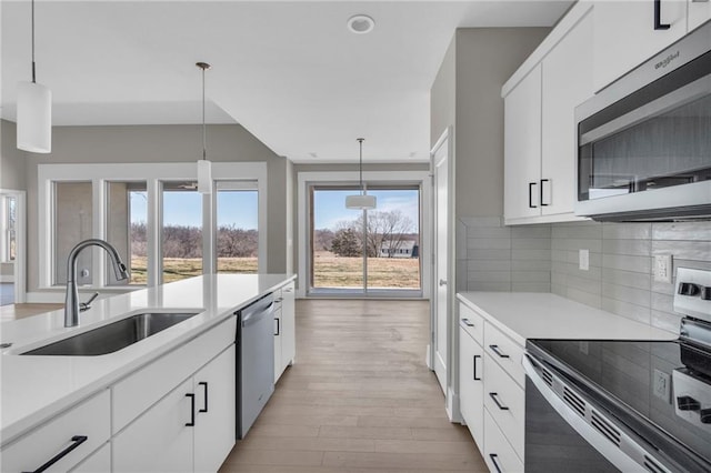 kitchen featuring a sink, light countertops, appliances with stainless steel finishes, backsplash, and light wood finished floors