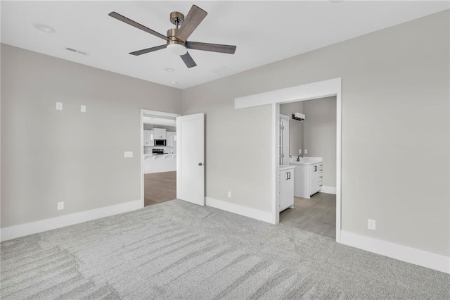 unfurnished bedroom with light carpet, a sink, visible vents, and baseboards