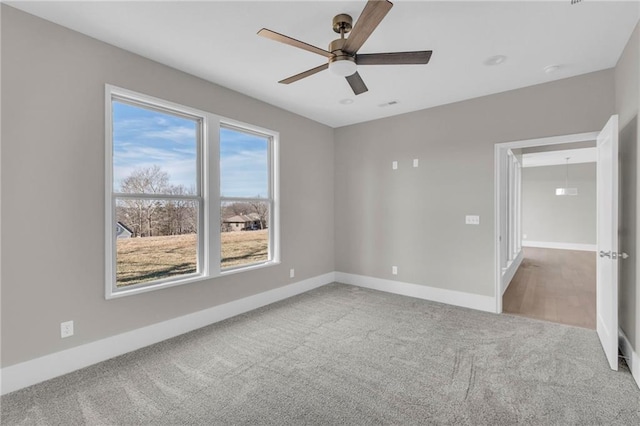 carpeted empty room featuring ceiling fan and baseboards