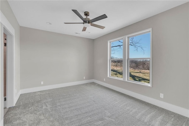 carpeted spare room featuring a ceiling fan and baseboards