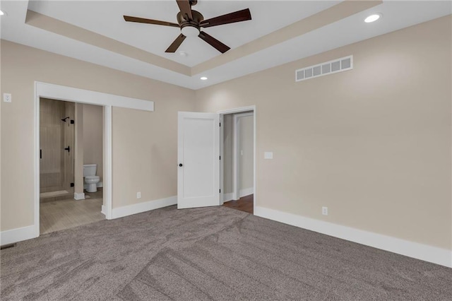 unfurnished bedroom with visible vents, a raised ceiling, carpet flooring, and recessed lighting