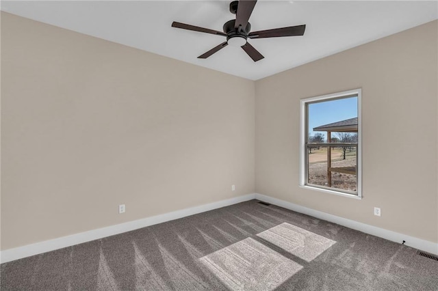 carpeted empty room with a ceiling fan, visible vents, and baseboards