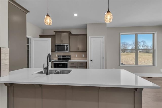 1111 Old Time Dr, Excelsior Springs, MO 64024 - kitchen with stainless steel appliances, light countertops, a sink, tasteful backsplash, and hanging light fixtures