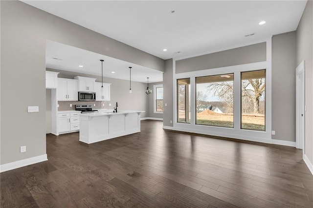 kitchen featuring stainless steel appliances, dark wood-type flooring, open floor plan, light countertops, and decorative backsplash