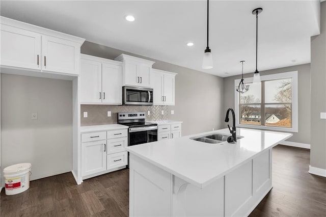 kitchen featuring a kitchen island with sink, a sink, white cabinetry, appliances with stainless steel finishes, and decorative backsplash