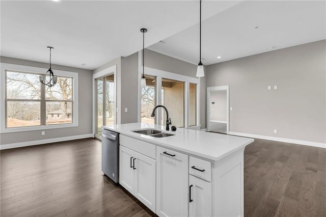 kitchen featuring a center island with sink, dark wood-style floors, light countertops, stainless steel dishwasher, and a sink