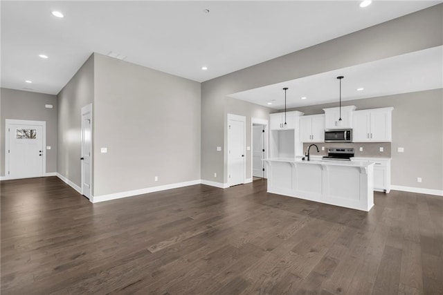 kitchen featuring open floor plan, stainless steel appliances, light countertops, and dark wood finished floors