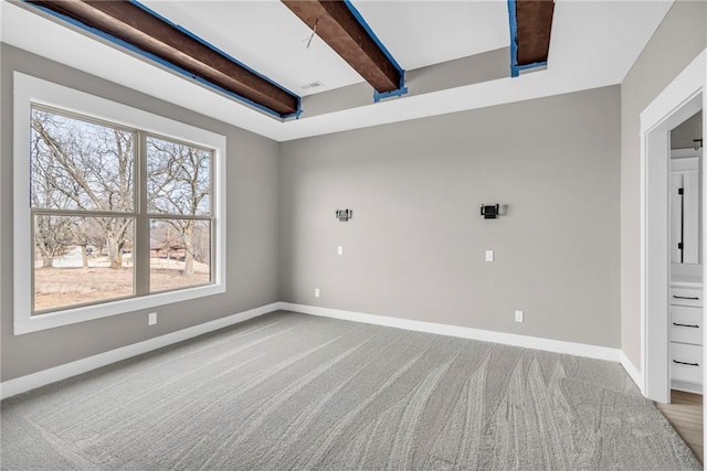 carpeted empty room featuring beamed ceiling and baseboards