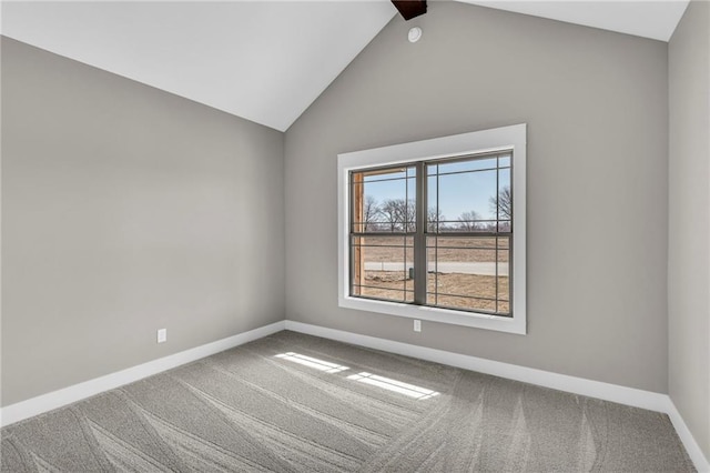 carpeted spare room with vaulted ceiling and baseboards