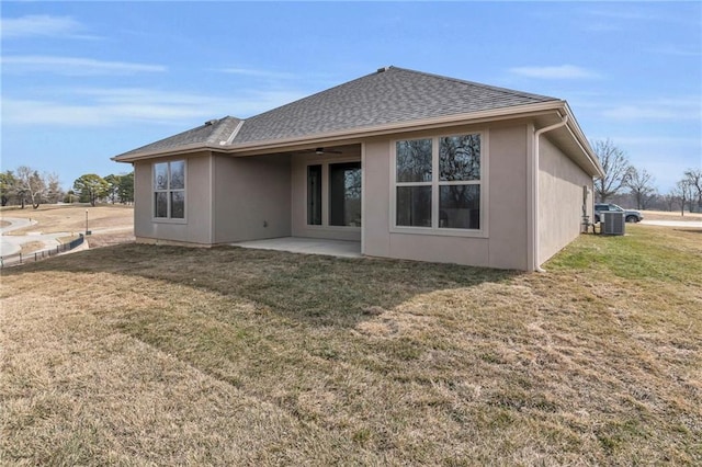 back of house with a patio, roof with shingles, a lawn, and a ceiling fan