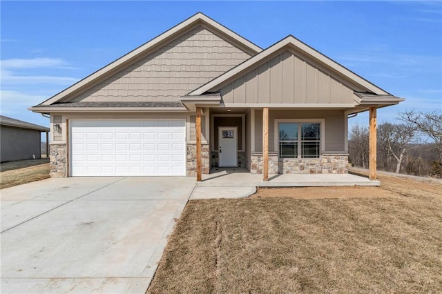 craftsman-style house with an attached garage, concrete driveway, a front lawn, and stone siding