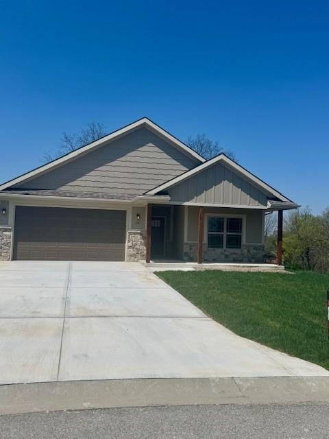 1112 Old Time Dr, Excelsior Springs, MO 64024 - view of front of home with concrete driveway, stone siding, board and batten siding, an attached garage, and a front yard