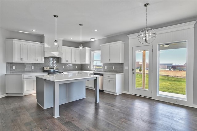 kitchen with decorative light fixtures, dark hardwood / wood-style floors, a kitchen island, stainless steel appliances, and white cabinets