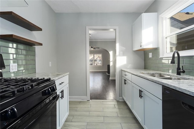 kitchen with white cabinetry, sink, light stone counters, and black appliances