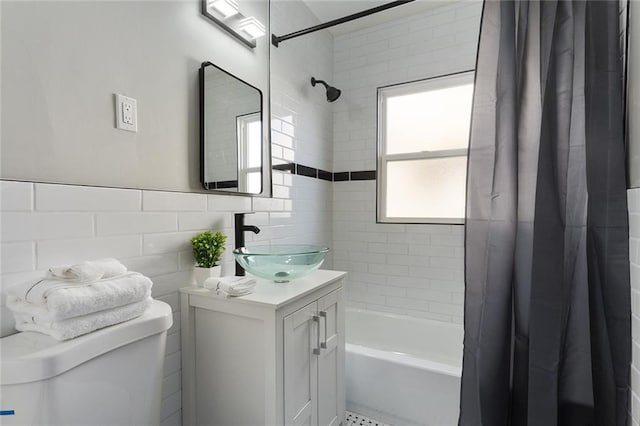 full bathroom featuring shower / bath combo with shower curtain, vanity, toilet, and tile walls