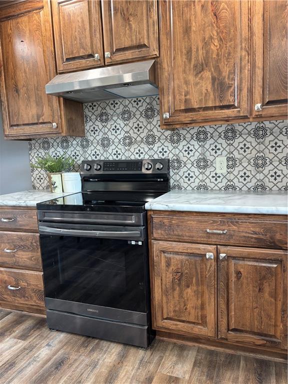 1202 NW County Road 6001, Butler, MO 64730 - kitchen with electric range, under cabinet range hood, light countertops, dark wood-style flooring, and tasteful backsplash