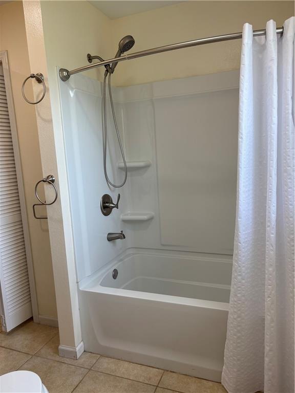 1202 NW County Road 6001, Butler, MO 64730 - full bathroom featuring tile patterned floors, shower / tub combo with curtain, baseboards, and toilet