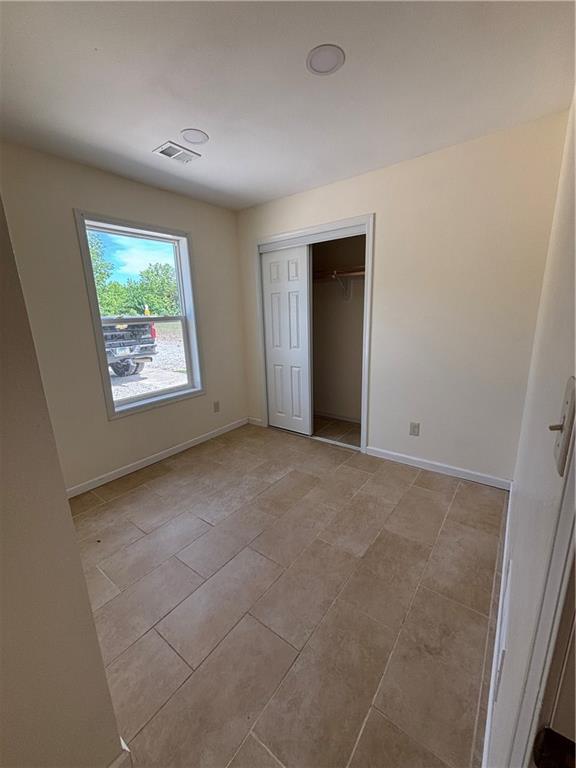 1202 NW County Road 6001, Butler, MO 64730 - unfurnished bedroom with baseboards, light tile patterned floors, and a closet