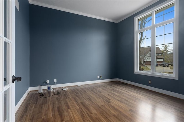 unfurnished room with crown molding, baseboards, and wood finished floors