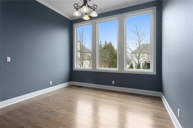 unfurnished room with a healthy amount of sunlight, a notable chandelier, baseboards, and wood finished floors