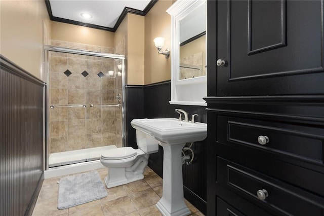 full bathroom with toilet, a stall shower, crown molding, and wainscoting