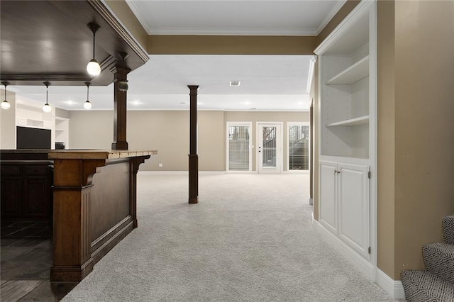 bar featuring crown molding, carpet flooring, baseboards, hanging light fixtures, and ornate columns