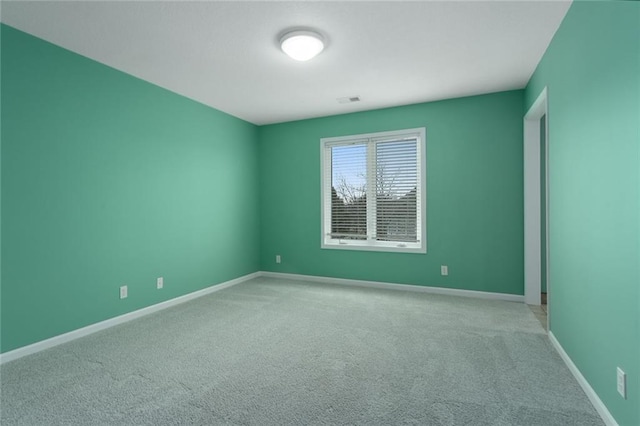 empty room featuring carpet floors, visible vents, and baseboards