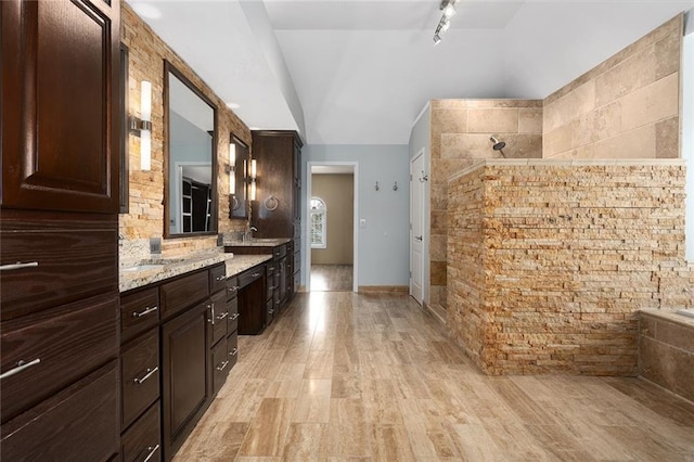 full bath with vaulted ceiling, walk in shower, wood finished floors, and vanity