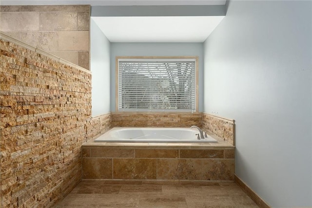 bathroom featuring brick wall and a bath