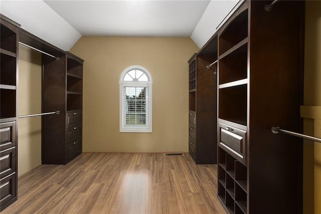 spacious closet featuring lofted ceiling, light wood finished floors, and visible vents