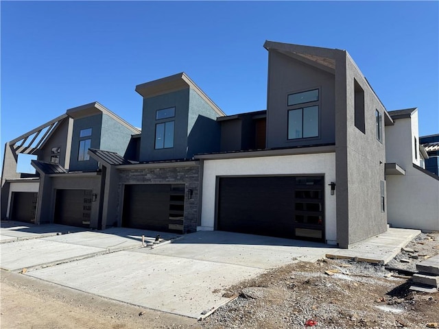 contemporary house with a standing seam roof, stucco siding, metal roof, and a garage