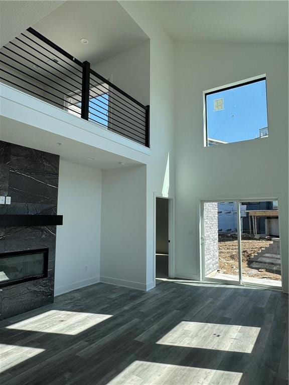 foyer with wood finished floors, a fireplace, baseboards, and high vaulted ceiling