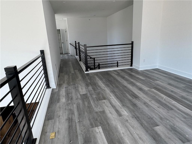 corridor featuring wood finished floors, an upstairs landing, and baseboards