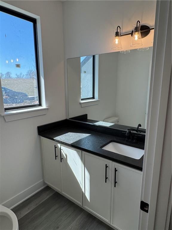 bathroom featuring vanity, toilet, wood finished floors, and baseboards