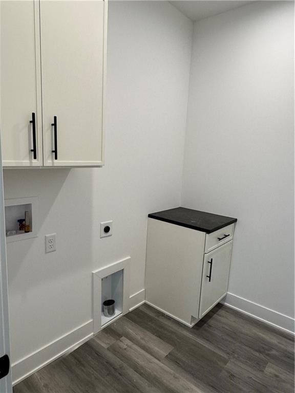 laundry area with baseboards, hookup for a washing machine, cabinet space, electric dryer hookup, and dark wood-style flooring