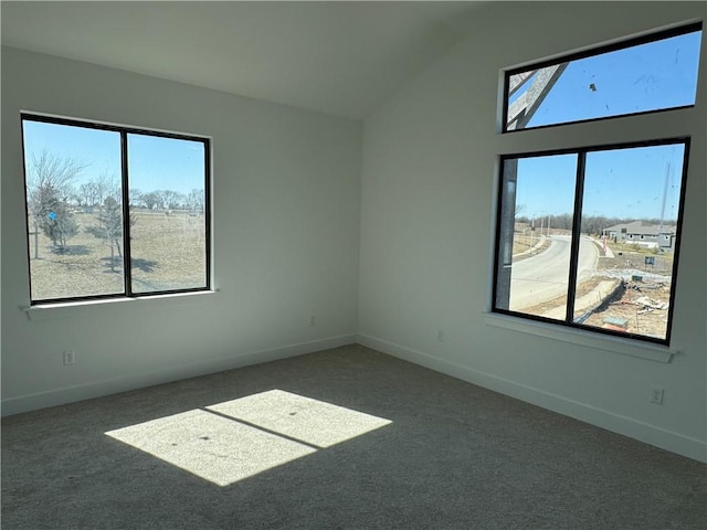 empty room featuring vaulted ceiling, carpet, and baseboards