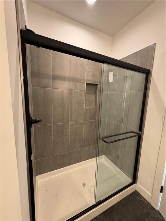 full bathroom with a stall shower and tile patterned flooring