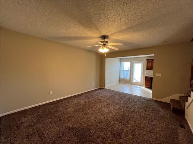 carpeted spare room featuring ceiling fan and a textured ceiling