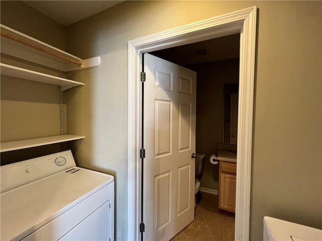 clothes washing area with washer / clothes dryer and light tile patterned floors