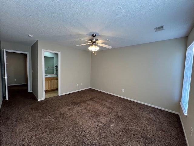 empty room featuring ceiling fan, a textured ceiling, and dark colored carpet