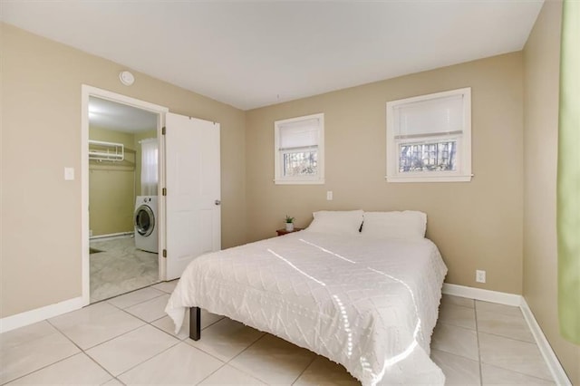 bedroom featuring a walk in closet, washer / dryer, and light tile patterned floors