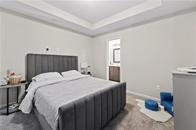 bedroom featuring ensuite bathroom, a raised ceiling, and carpet