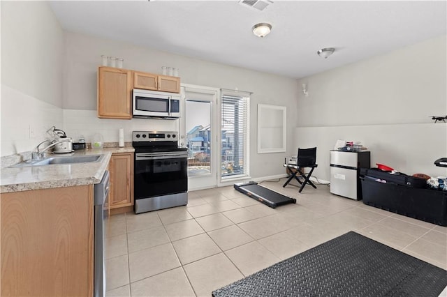 kitchen featuring stainless steel appliances, light brown cabinetry, sink, and light tile patterned floors