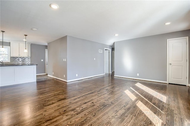 unfurnished living room featuring dark wood-style floors, baseboards, and recessed lighting