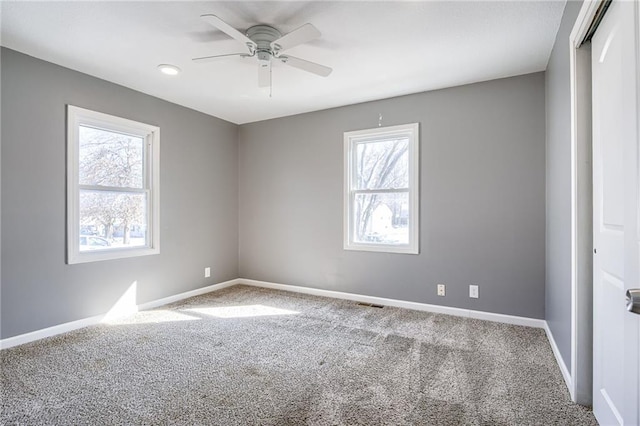 empty room with baseboards, a healthy amount of sunlight, and carpet flooring